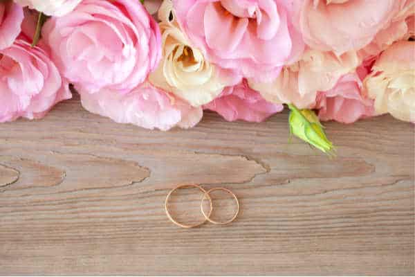 flowers with wedding rings on wood