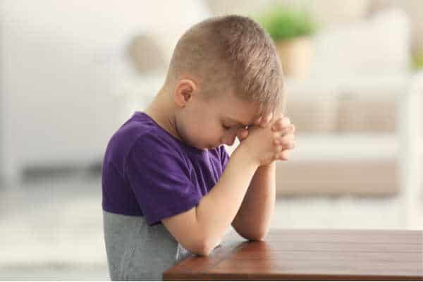 Kid in purple shirt praying in a kids war prayer room 