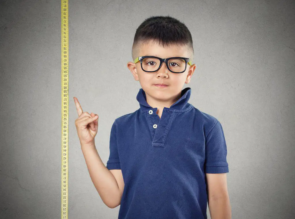 Little boy pointing to a measuring tape - frustrated by being short 