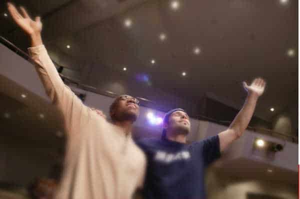 Two men with hands raised in worship - find a church your husband likes 