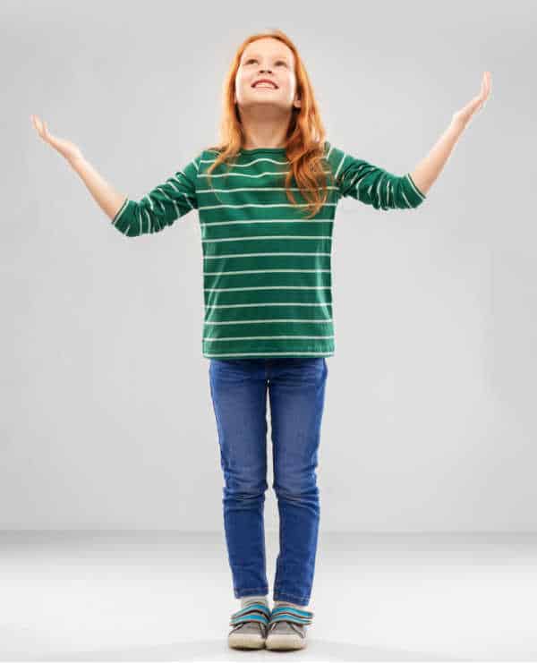 Young girl with her face lit up and hands lifted up - a picture of gratitude for God's gifts because her parents teach kids to declutter biblically. 