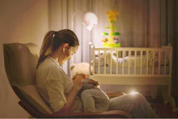 Sleep deprived mom nursing her newborn in the dark of night. Tired mom care giving while others are asleep.