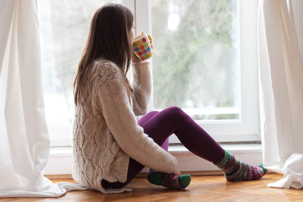 homeschool mom drinking coffee sitting in a lonely wintery room - a picture of homeschool mom burnout