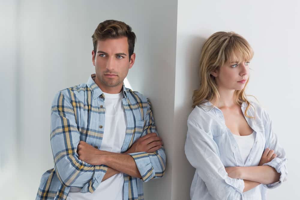 Couple fighting and standing on opposite sides of a wall, not looking at each other.  Obviously, they need Christian marriage counseling. 