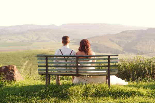 Young married couple sitting on a bench starring out at a beautiful mountain scene not knowing that they need preventative Christian marriage counseling.