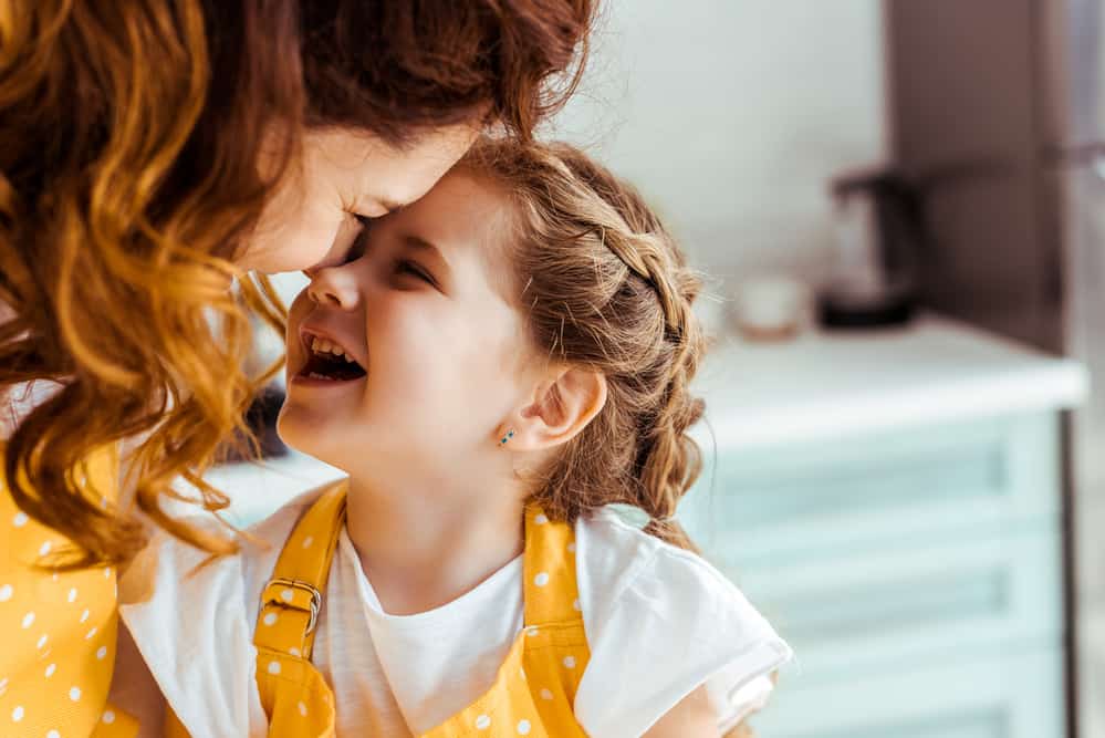 Mom and young daughter with yellow aprons, laughing and having fun in the kitchen.  Teach Kids Good stewardship of time and this mom has more time to have fun with her kids.