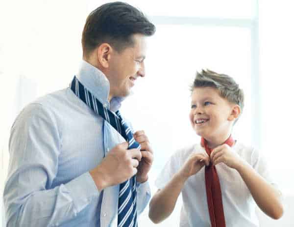 Dad and son putting on ties while they are getting dressed for church 