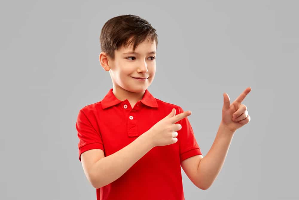 Happy, young boy pointing his fingers.  This kid dressed for church in a red polo shirt. 