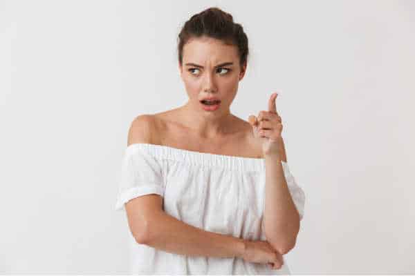 Woman in white shirt on a white background with her hand lifted and her face dubious as she questions your call.