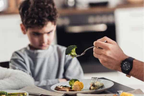 Little boy who is being offered brocolli by his father and he has his mouth firmly shut and his arms crossed.  He is ungrateful just like when God's kids complained about His cooking too. 