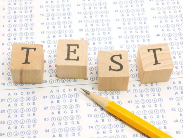 A standardized test with a sharpened number 2 pencil and blocks that spell out test - the importance of Sunday school should be shown in testing