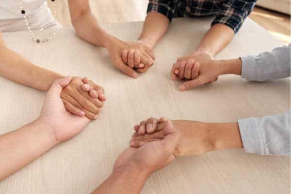 Group of women holding hands on a table - supporting each other through miscarriage fears, pregnancy fears