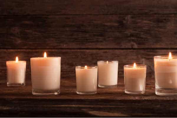 six white candles glowing on a wooden background set up like a memorial to lost children for women with miscarriage fears