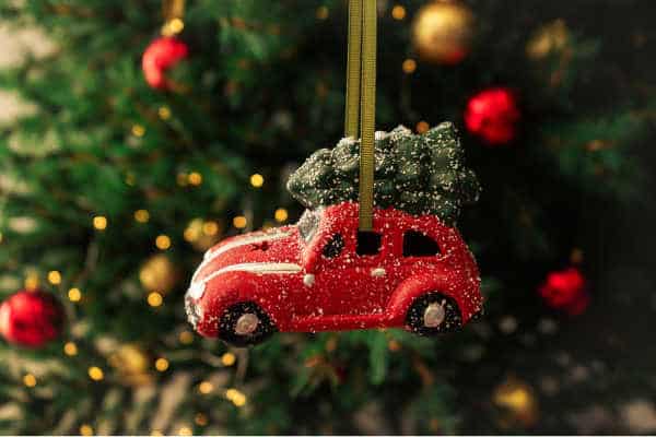 Little toy car ornament with Christmas tree to symbolizing traveling while homeschooling during the holidays. 