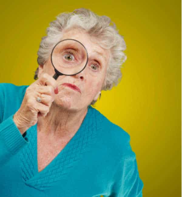 Elderly woman with white hair and a blue shirt holding up a magnifying glass as she prepares to interrogate your child about homeschooling. 