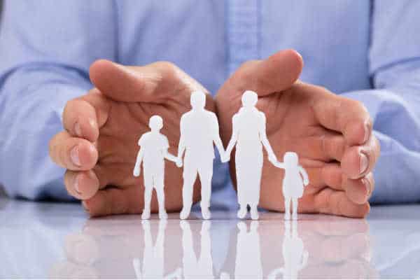 Father and Husband's hands surrounding his family - a paper cut out of parents with kids. Symbolizes what it looks like to set boundaries with family regarding homeschooling and protecting your family from anti-homeschooling relatives.