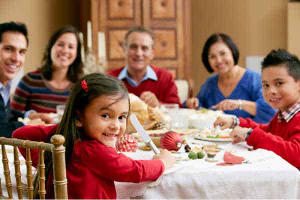 Set boundaries with your family regarding homeschooling and be able to enjoy a peaceful joy family dinner like the one pictured here.  Family is seated around a giant turkey, dressed in bright primary colors. 