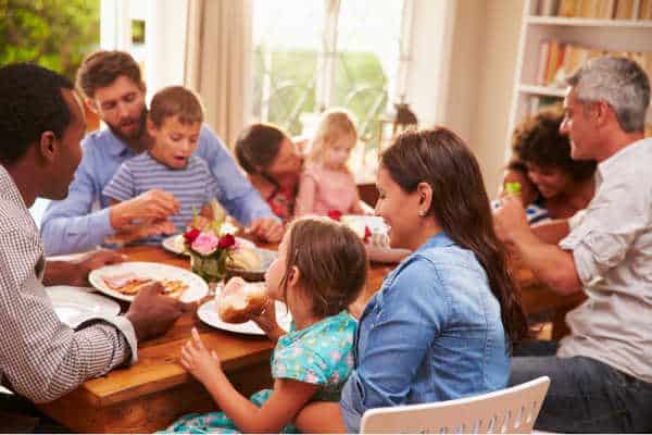 Set boundaries with family regarding homeschool and be able to enjoy a happy family gathering like the one pictures.  A diverse family with adults and children laughing and eating. 