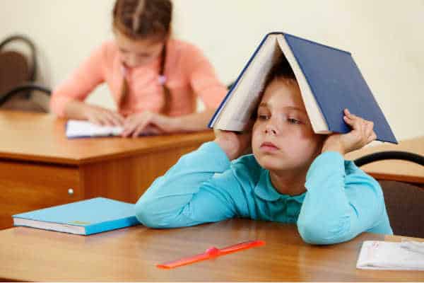 Little boy in a Sunday School room who is bored, and has parents who dislike the children's ministry.  He has a book over his head. 