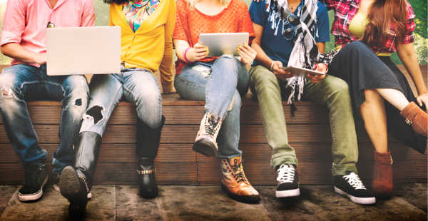 Group of teens gathered outside on a wall, because they dislike the children's ministry at church.  All you see is there feet dangling over the side.