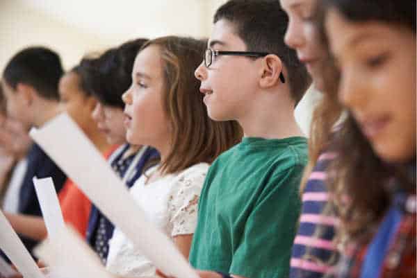 Group Of School Children Singing In Choir Together, they like to sing but dislike the children's ministry. 