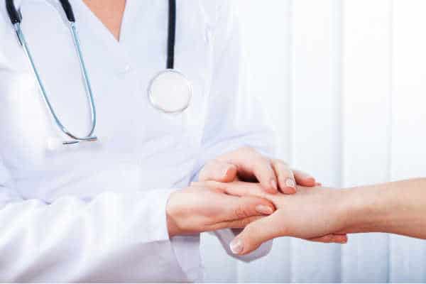 Female doctor with stethoscope. Holding another woman's hand and comforting her because she is homeschooling with depression