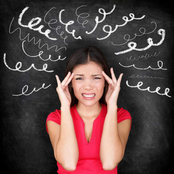 bible verses for homeschool moms should help reduce the stress of this overwhelmed mom.  She has a red short-sleeved shirt on.  Her hands are at her temples and her face looks pained.  Behind her is a blackboard with curlycue lines coming out from her head in a fan. 