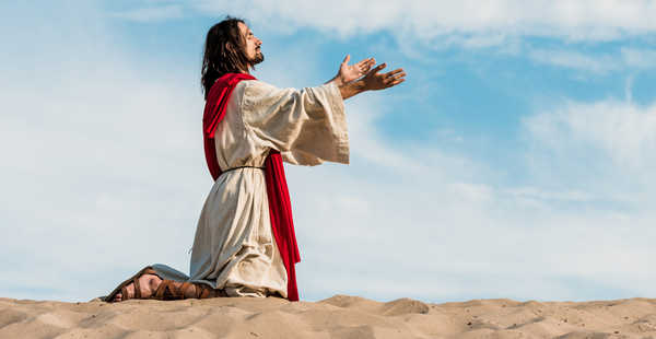 Picture of someone representing Jesus praying on his knees with his hands raised up.