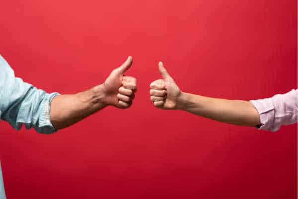 Red background.  Two people giving thumbs up - one a woman and one a man.  They are parents who have a united front to get kids to focus for online worship. 