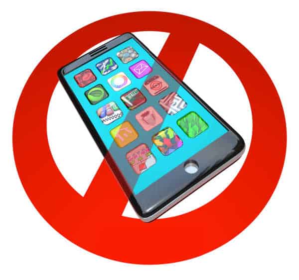 A red No or Stop sign over a smart phone showing apps - it is hard to get kids to focus for online worship if they have their phones. Just say no symbol over a phone. 