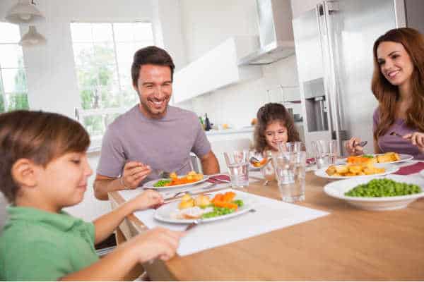 Family smiling around a good meal in kitchen, after kids focus for online church, this family gathers to continue talking about the service and the message that was delivered. 