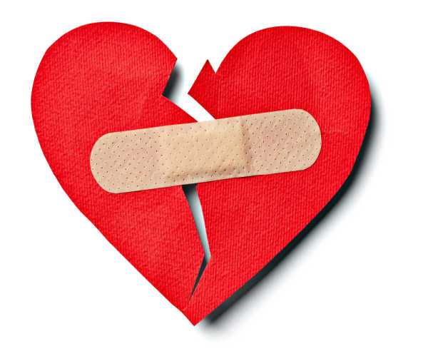 Red paper heart that is cut down the middle a band-aid is trying to bring it back together - this exemplifies the damage that a bossy child can wreck on relationships.