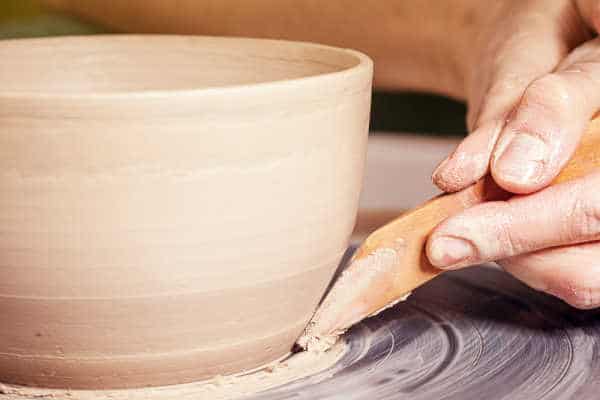 Close-up Woman potter beautifully sculpts from brown clay and equals a spatula with a deep plate on a potter's wheel in a beautiful workshop - pottery in the Bible