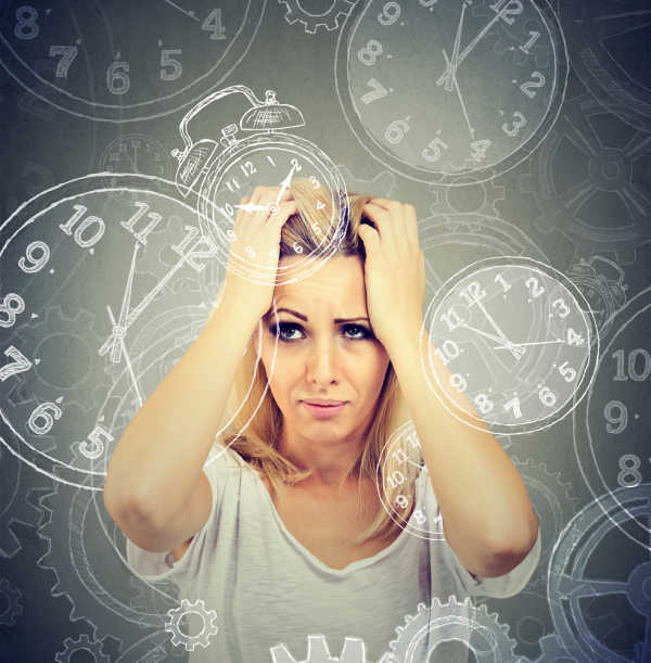 Woman in white top gripping her head.  She longs to simpify your family life with clocks spinning all around her head. 