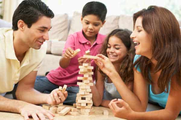 Family in their living room playing Jenga, when you simplify your family life there is time to play games.