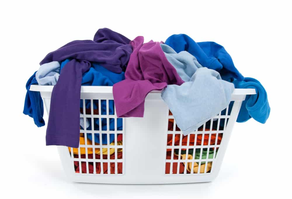 Colorful clothes in a laundry basket on white background. Blue, indigo, purple that needs to be folded by an unappreciated mom.